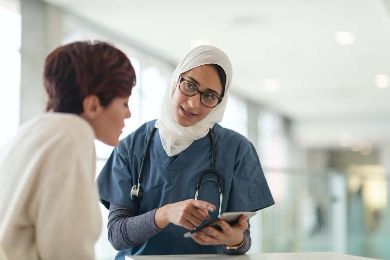 Picture3 Doctor in blue scrubs reading off of tablet while speaking to patient