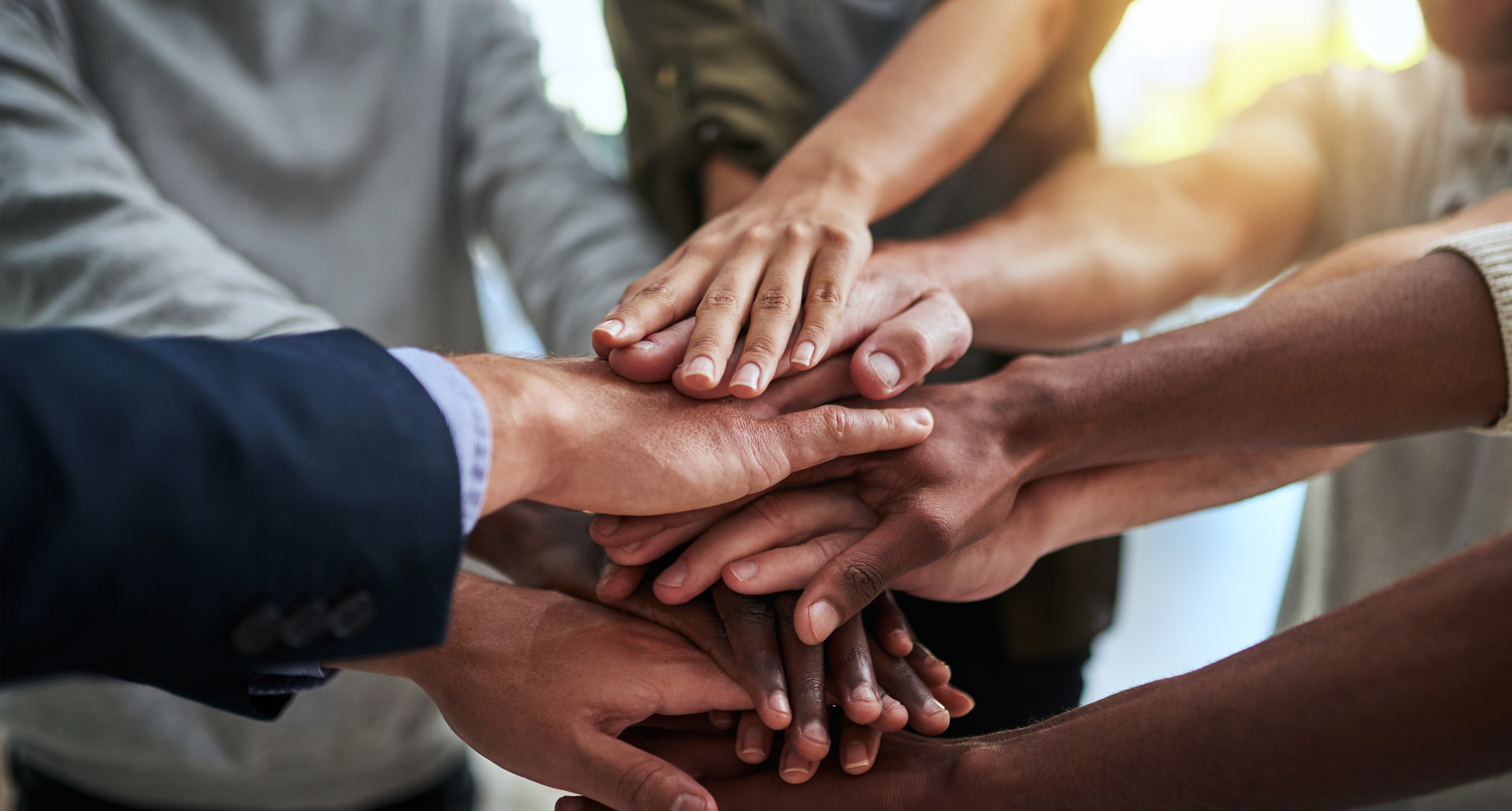 iStock-889029082 diversity hands LI Header hands of a wide variety of skin colors stacking on top of one another to indicate teamwork